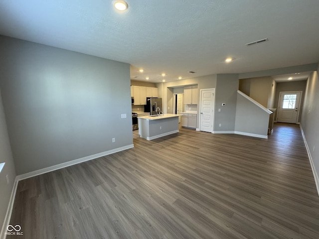 unfurnished living room featuring stairway, baseboards, visible vents, and dark wood-style flooring