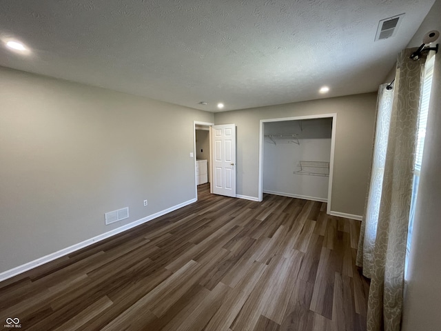 unfurnished bedroom featuring dark wood-type flooring, visible vents, a textured ceiling, and baseboards