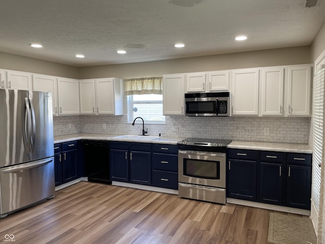 kitchen featuring a sink, white cabinetry, light countertops, appliances with stainless steel finishes, and light wood-type flooring