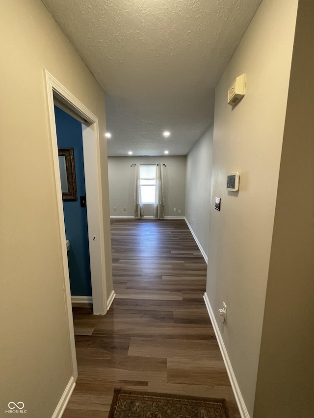 hall with a textured ceiling, recessed lighting, wood finished floors, and baseboards