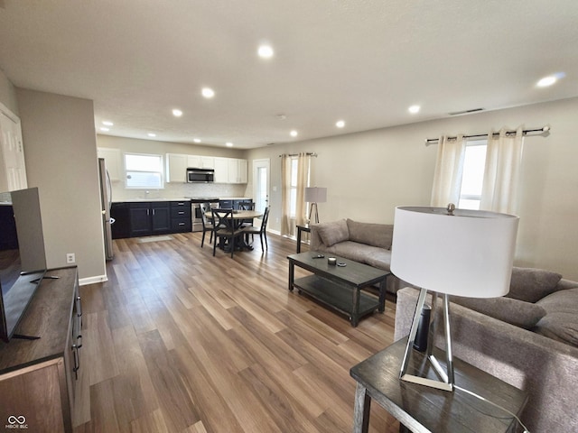 living area featuring recessed lighting, wood finished floors, and a healthy amount of sunlight