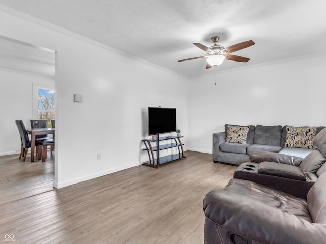 living area with crown molding, baseboards, ceiling fan, and wood finished floors