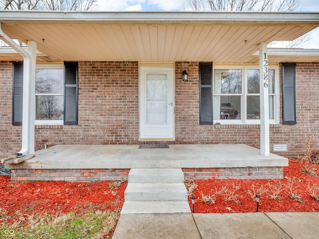 property entrance featuring a porch and brick siding