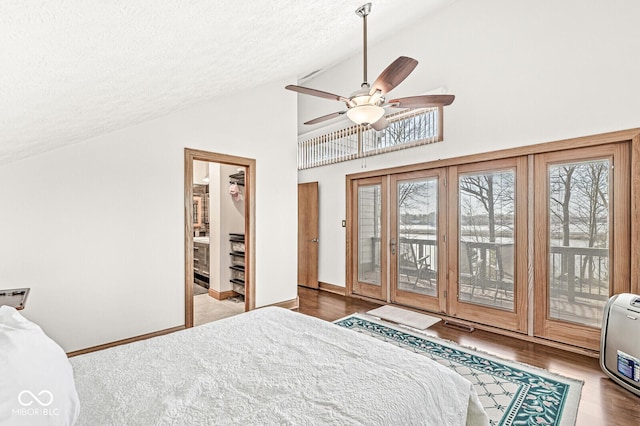 bedroom featuring a spacious closet, a textured ceiling, wood finished floors, access to outside, and baseboards