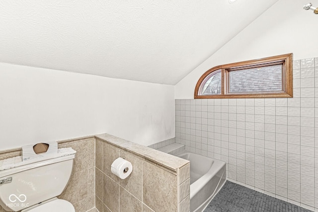 full bath with a garden tub, tile walls, lofted ceiling, toilet, and a textured ceiling