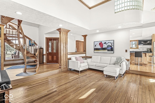 living room featuring decorative columns, a wealth of natural light, stairway, a high ceiling, and hardwood / wood-style flooring