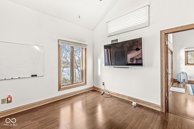 unfurnished room with lofted ceiling, visible vents, baseboards, and wood finished floors