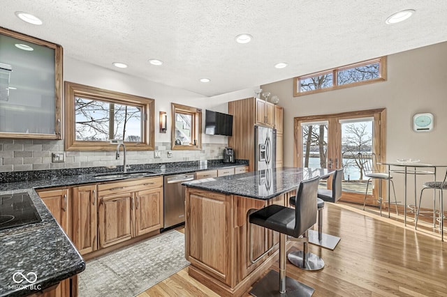 kitchen featuring light wood-style flooring, a breakfast bar, a sink, appliances with stainless steel finishes, and a center island