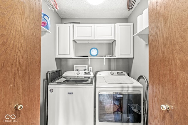 laundry room featuring cabinet space, a textured ceiling, and washing machine and clothes dryer