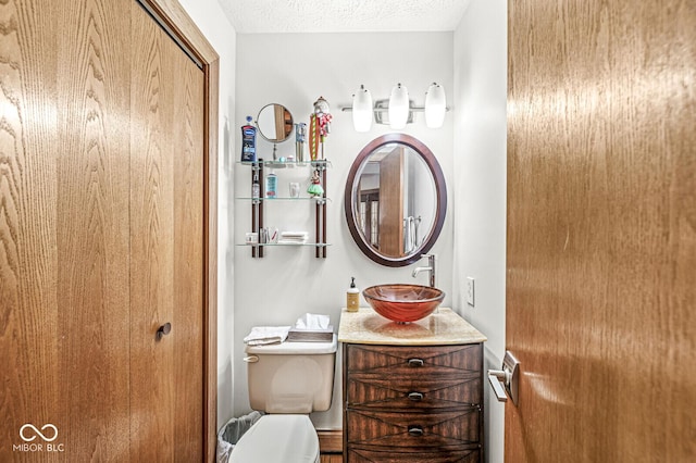 bathroom featuring toilet, a textured ceiling, and vanity