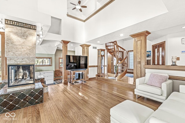 living room featuring hardwood / wood-style flooring, decorative columns, stairway, and a tile fireplace