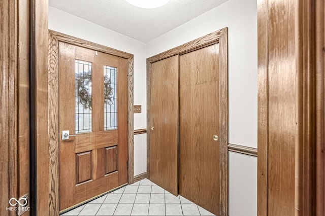 foyer entrance with a textured ceiling and light tile patterned floors