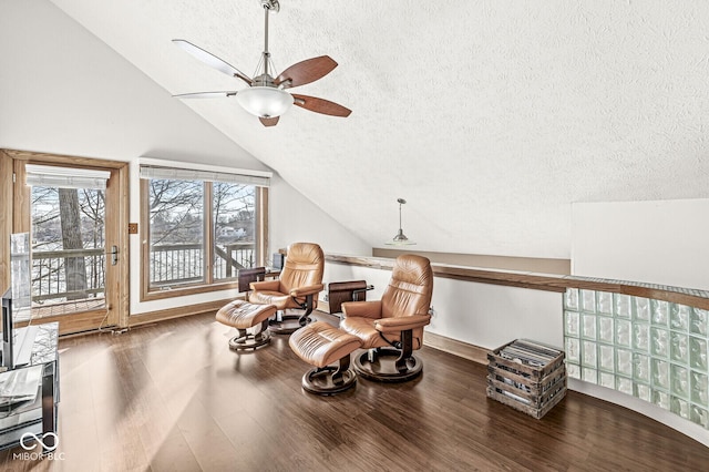 sitting room with baseboards, a ceiling fan, lofted ceiling, wood finished floors, and a textured ceiling