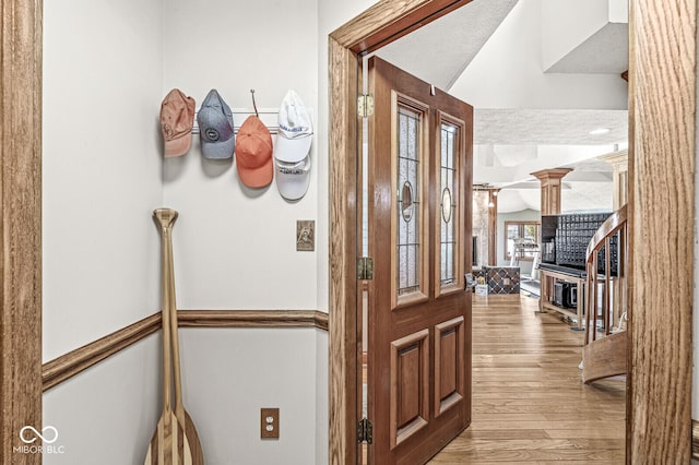 entrance foyer with lofted ceiling, decorative columns, and wood finished floors