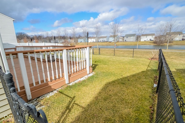 view of yard with a fenced backyard, a residential view, and a deck with water view