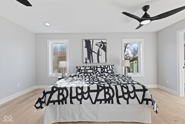 bedroom featuring light wood finished floors, multiple windows, and baseboards