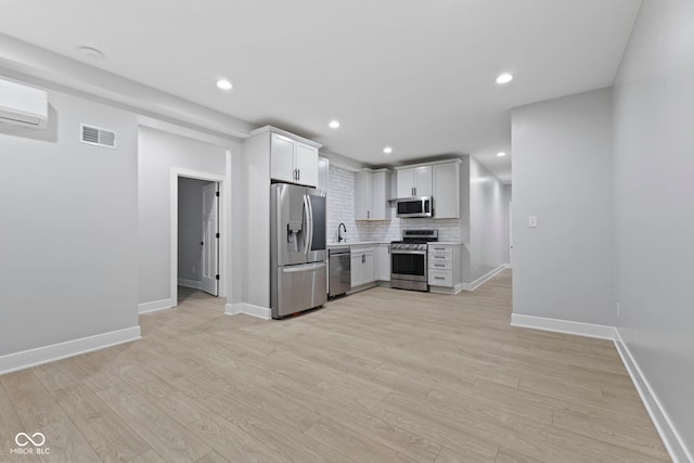 kitchen with tasteful backsplash, visible vents, light wood-style flooring, stainless steel appliances, and light countertops