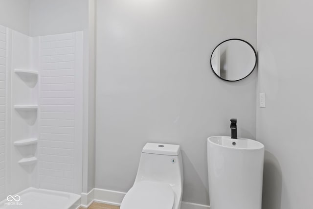 bathroom featuring walk in shower, toilet, and baseboards