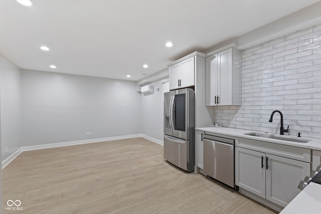 kitchen featuring stainless steel appliances, tasteful backsplash, light countertops, light wood-style floors, and a sink