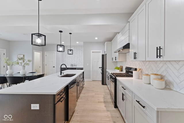 kitchen with a sink, wall chimney range hood, black range with gas stovetop, freestanding refrigerator, and dishwasher