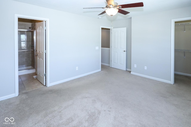 unfurnished bedroom featuring carpet floors, a closet, a spacious closet, ceiling fan, and baseboards