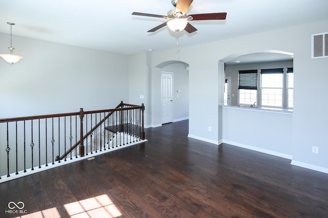 unfurnished room featuring arched walkways, visible vents, baseboards, and wood finished floors