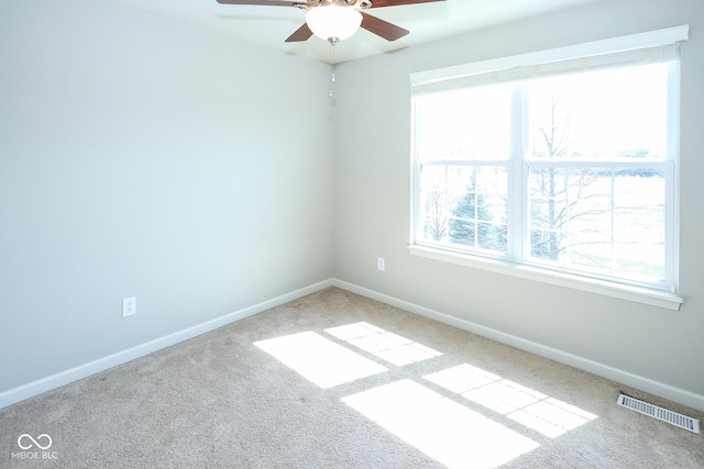 carpeted spare room with a ceiling fan, visible vents, and baseboards