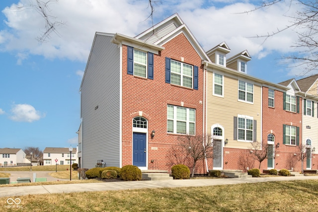 view of property featuring brick siding, a front lawn, and a residential view