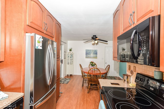 kitchen featuring decorative backsplash, light wood-style floors, ceiling fan, light stone countertops, and black appliances