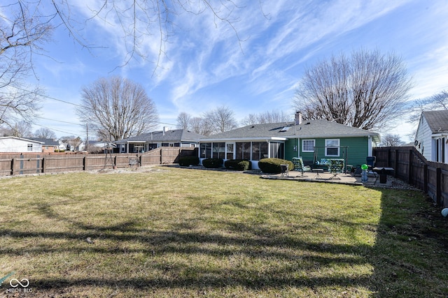 back of property with a fenced backyard, a sunroom, a lawn, a chimney, and a patio area