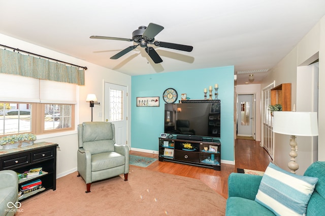 living area with a ceiling fan, baseboards, and wood finished floors