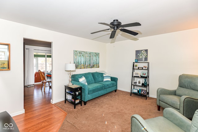 living area featuring ceiling fan, light wood-style flooring, and baseboards