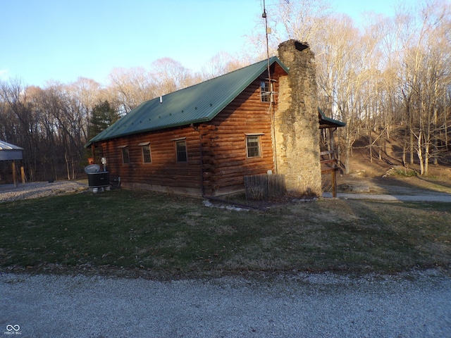 view of side of home with metal roof, a yard, a chimney, and log siding