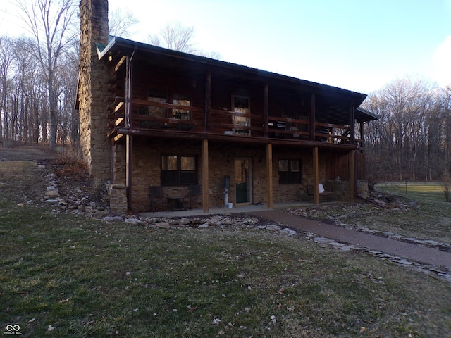 rear view of property with a lawn, a patio area, a deck, log siding, and stone siding