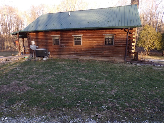 view of home's exterior with a yard, a chimney, cooling unit, and log siding