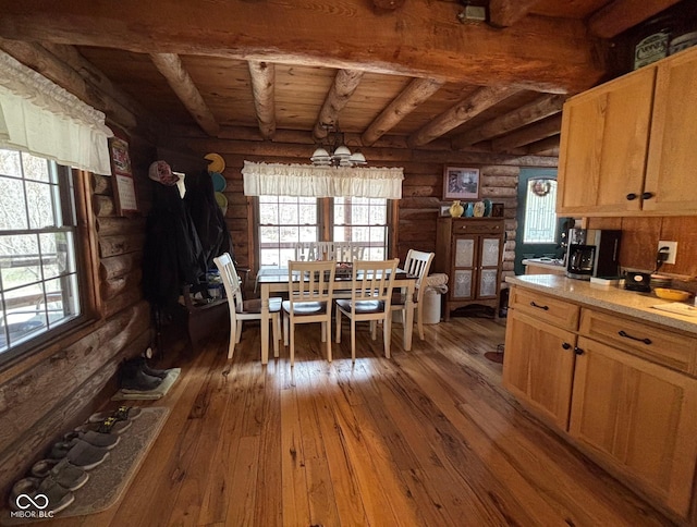 unfurnished dining area featuring a healthy amount of sunlight, dark wood-type flooring, and beamed ceiling