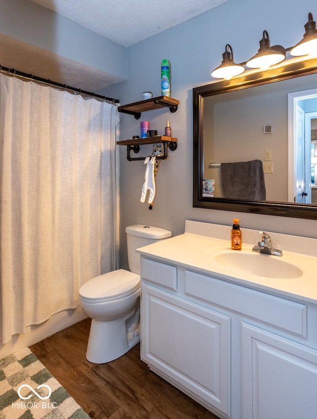 bathroom featuring toilet, curtained shower, wood finished floors, and vanity