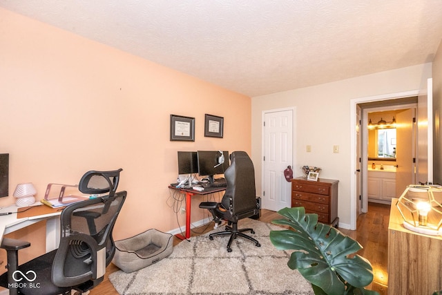 office area featuring a textured ceiling, baseboards, and wood finished floors