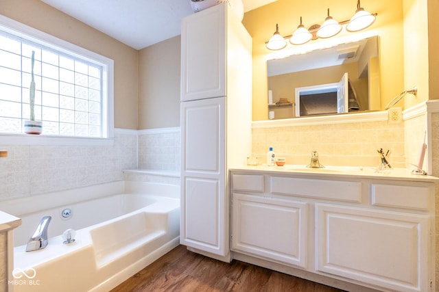 bathroom featuring vanity, a bath, and wood finished floors