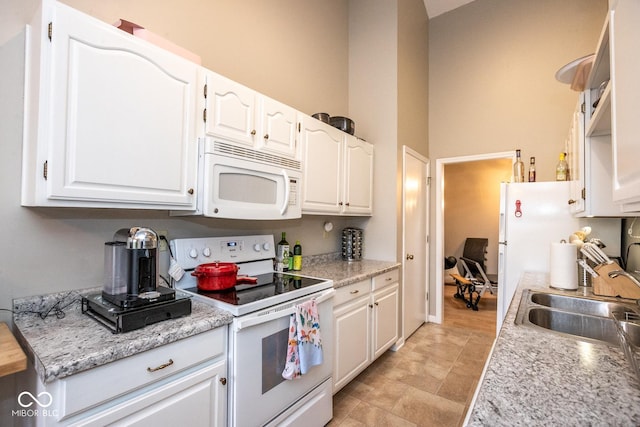 kitchen with light countertops, white appliances, a sink, and white cabinetry