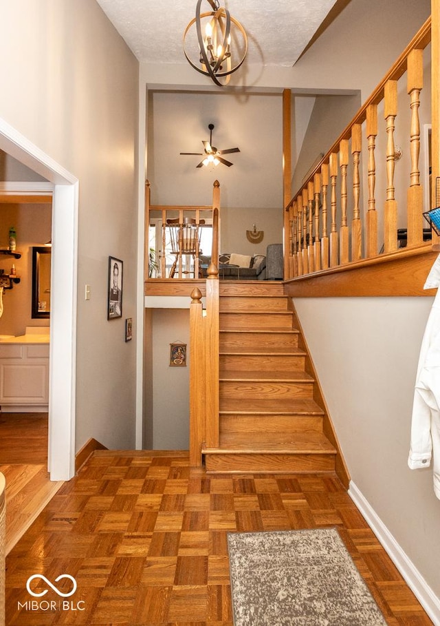 staircase with ceiling fan with notable chandelier