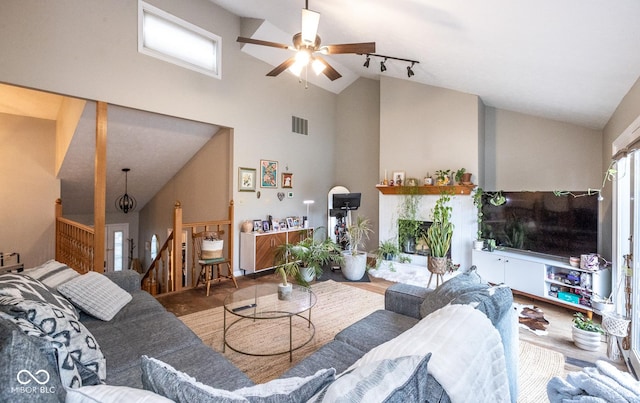 living area featuring a fireplace with raised hearth, track lighting, visible vents, and a healthy amount of sunlight