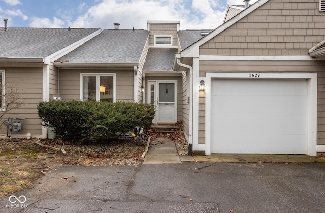 view of front facade featuring an attached garage, aphalt driveway, and roof with shingles