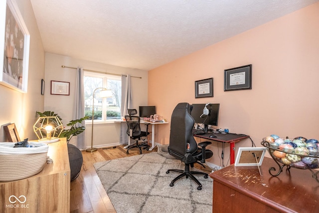 office area with hardwood / wood-style flooring, baseboards, and a textured ceiling