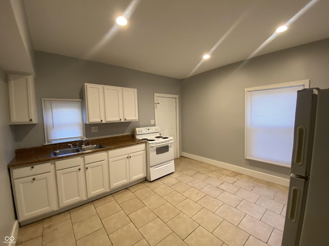 kitchen featuring dark countertops, white appliances, white cabinets, and a sink