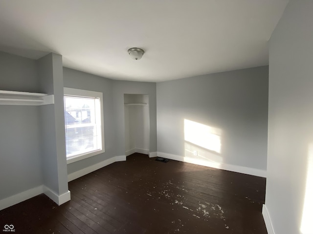 unfurnished bedroom featuring hardwood / wood-style floors, visible vents, and baseboards