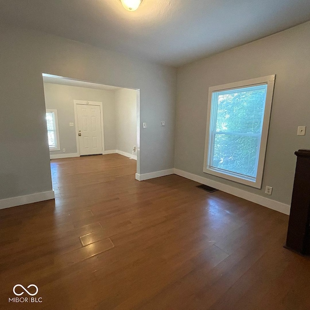 unfurnished room with dark wood-style floors, visible vents, and baseboards