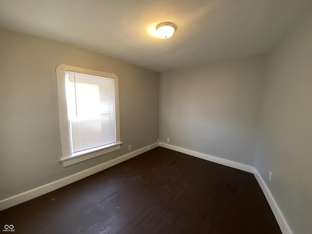 empty room with dark wood-style floors and baseboards