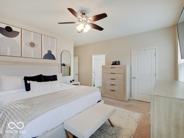 bedroom featuring light carpet, ceiling fan, and ensuite bathroom