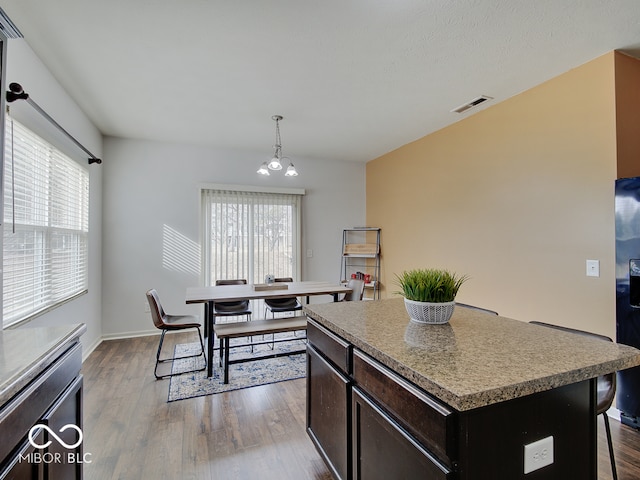 kitchen with a kitchen island, visible vents, a breakfast bar, and wood finished floors